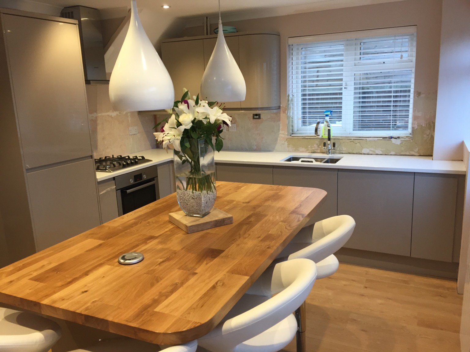 Completed taupe kitchen with rounded solid timber island and pendant lights
